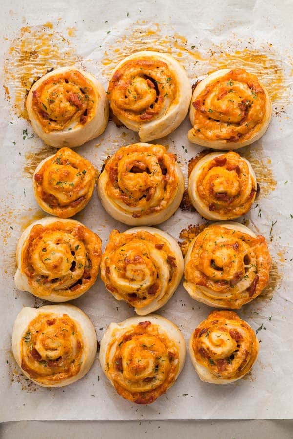 These Homemade Pizza Rolls are made with easy homemade pizza dough, pepperoni, pizza sauce and cheese! Make ahead and freezer friendly! #pizza #recipes #dinner close up overhead image of baked pizza rolls on pan