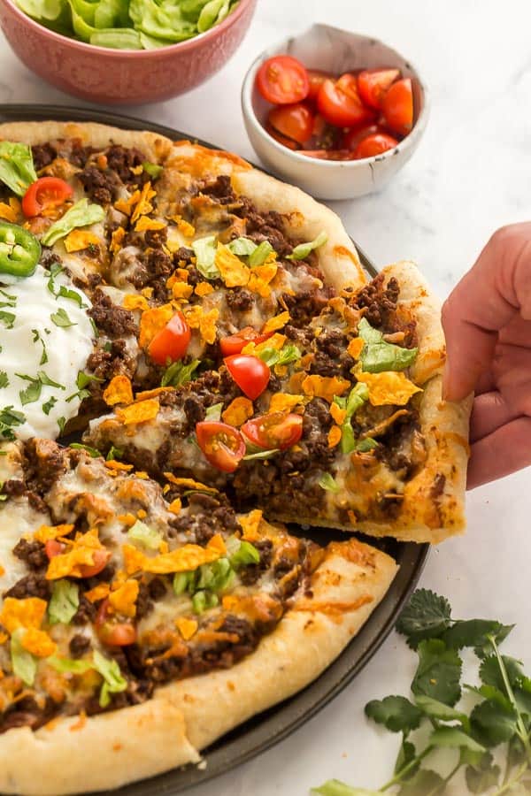 hand pulling out slice of taco pizza