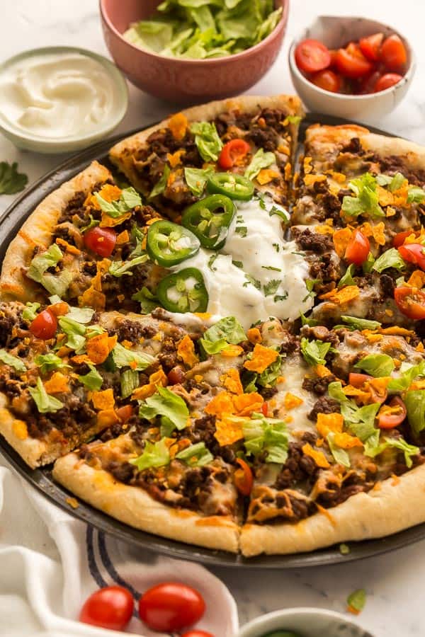 close up image of taco pizza with lettuce tomatoes and chips