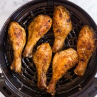 overhead image of cooked chicken drumsticks in air fryer basket