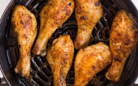 overhead image of cooked chicken drumsticks in air fryer basket