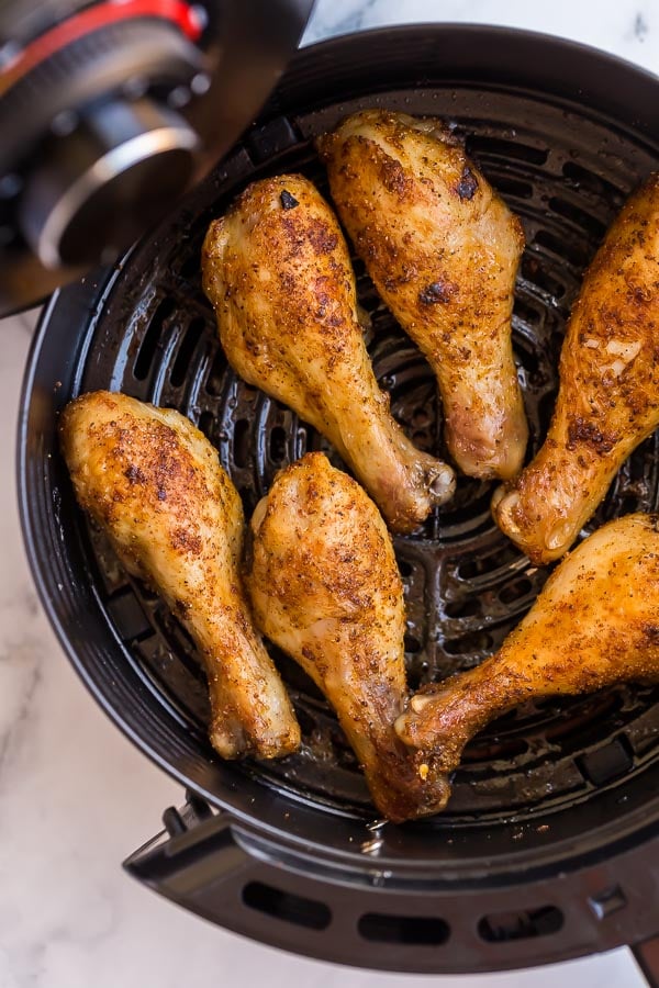 close up of crispy chicken legs in air fryer basket