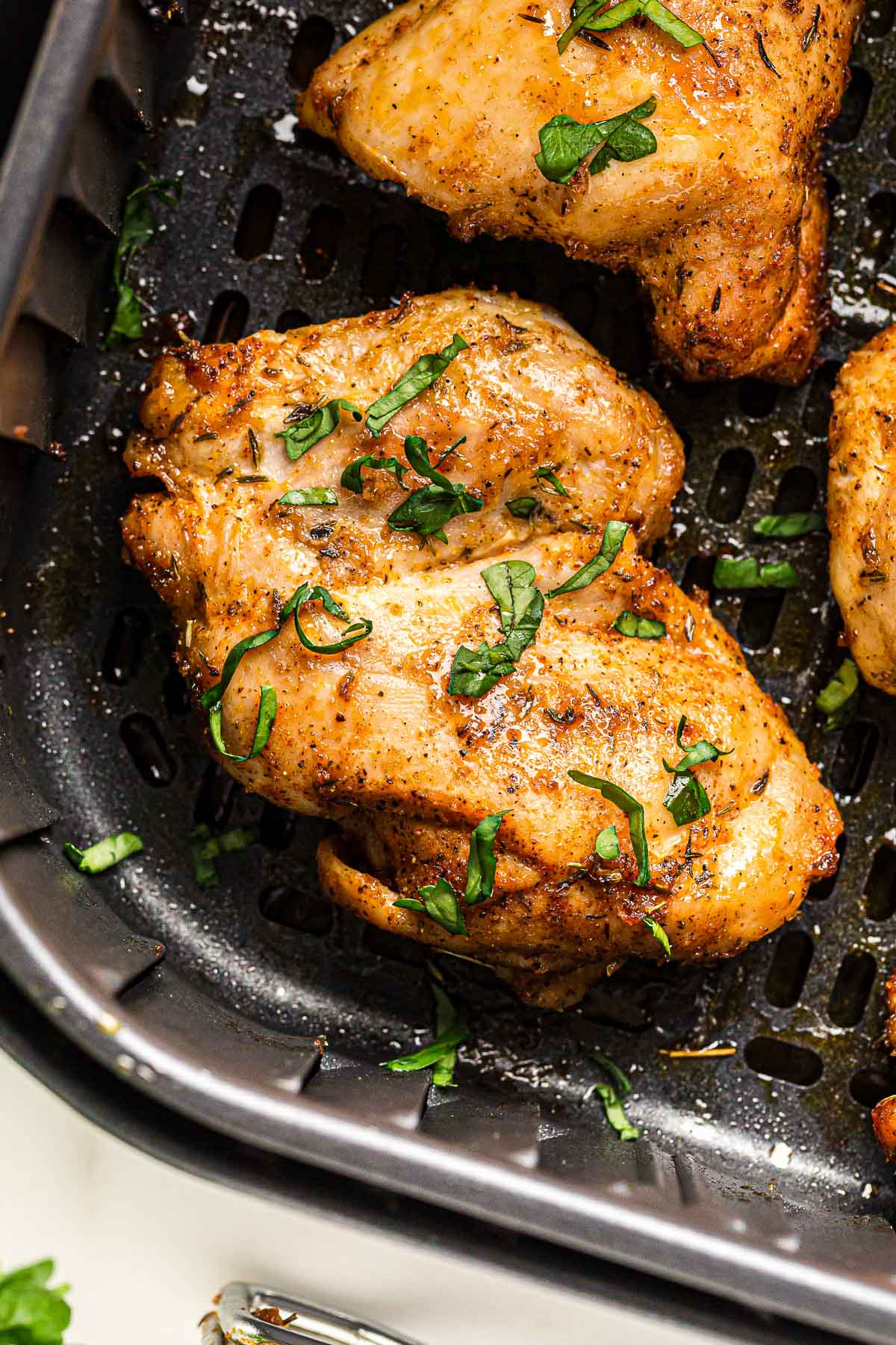 close up image of boneless chicken thigh in air fryer.