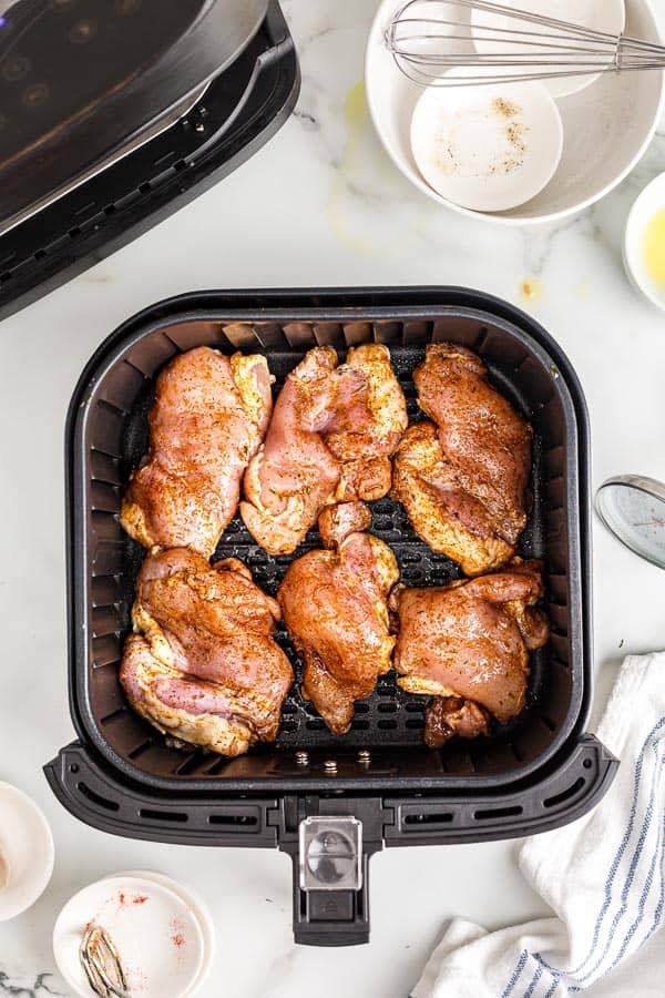 uncooked chicken thighs in air fryer basket