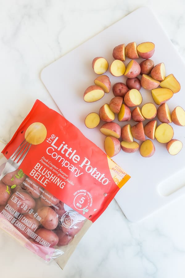 halved potatoes on cutting board with bag of Little potatoes