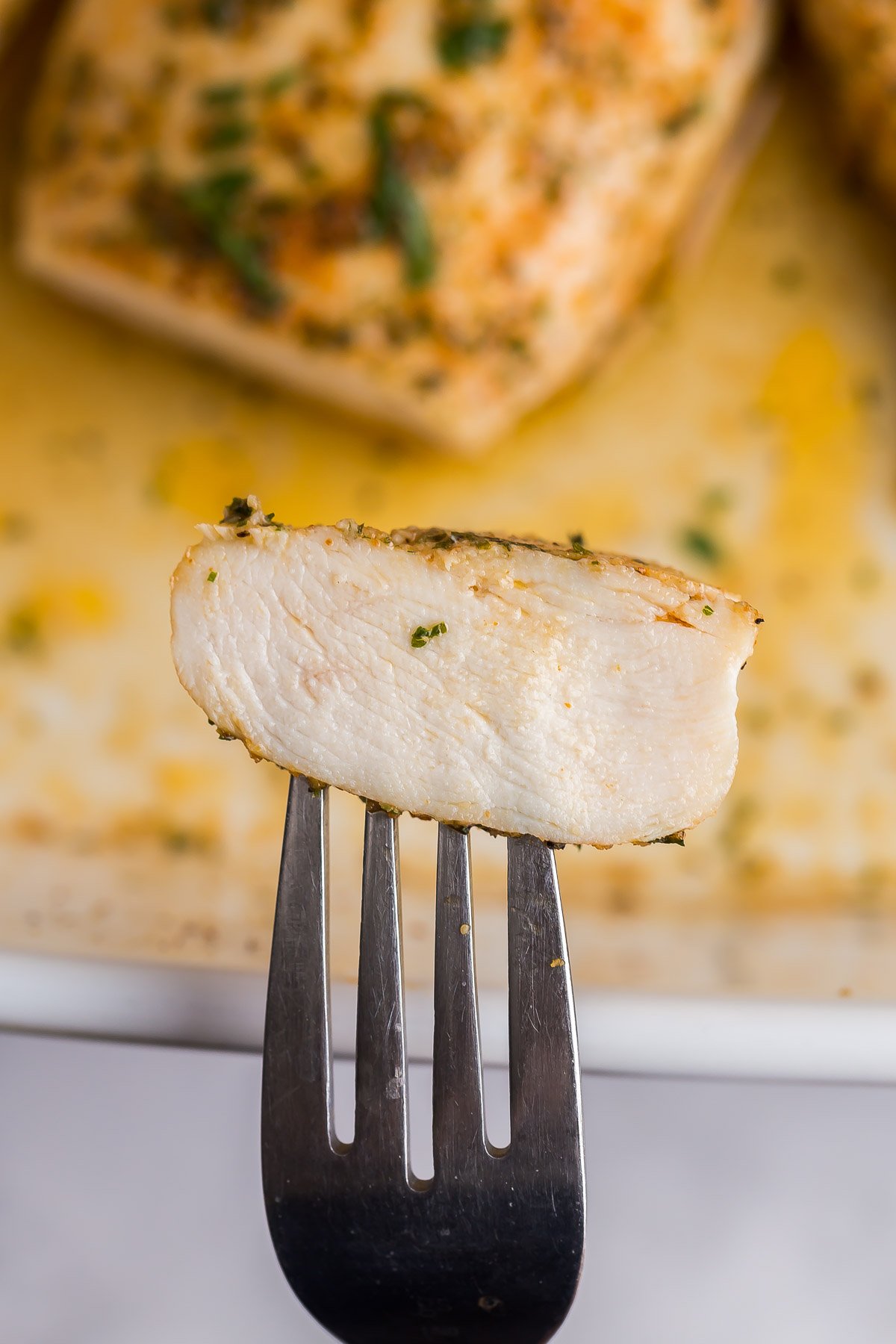 one slice of baked chicken breast on a fork.