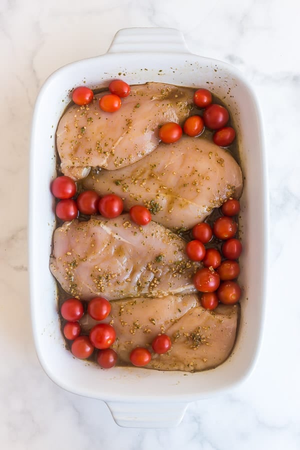 uncooked chicken breasts with caprese marinade and cherry tomatoes