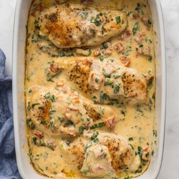 square image of baked tuscan chicken in baking dish.