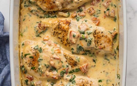 square image of baked tuscan chicken in baking dish.