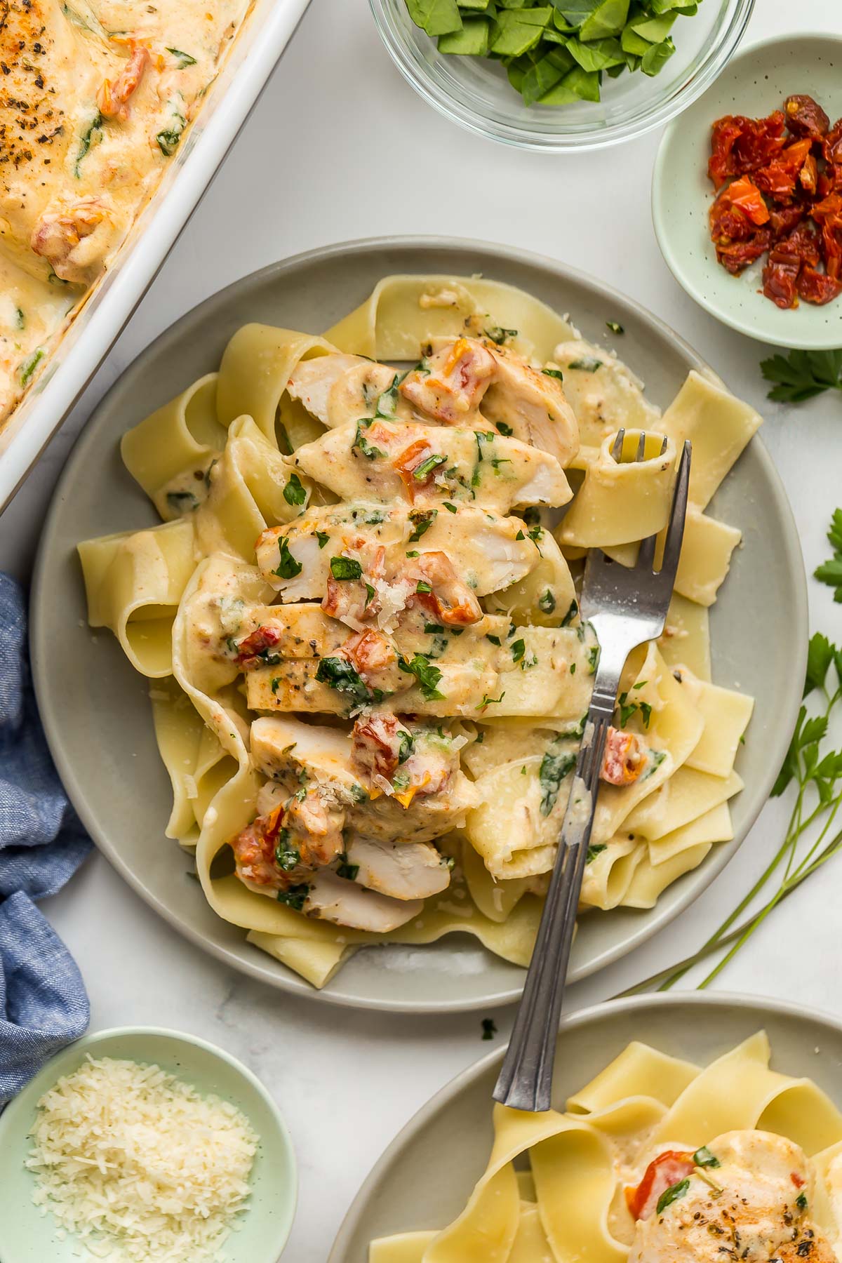 overhead image of sliced tuscan chicken on pappardelle pasta.