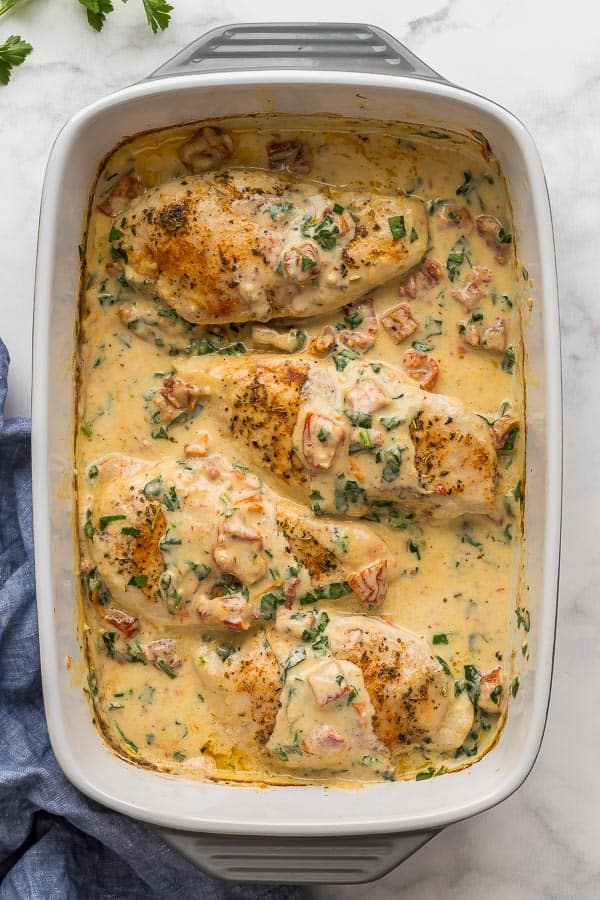 overhead image of tuscan chicken breasts in white baking dish