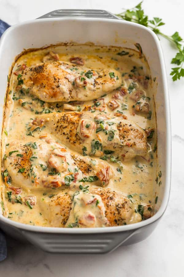 close up image of tuscan chicken in white baking dish