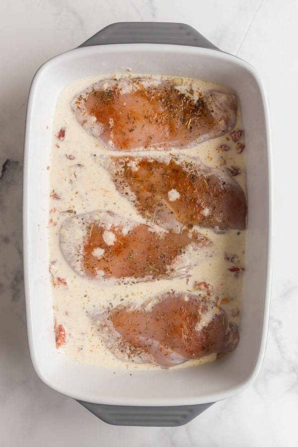 tuscan sauce poured over raw chicken breasts