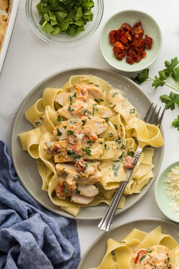 sliced tuscan chicken over noodles on grey plate
