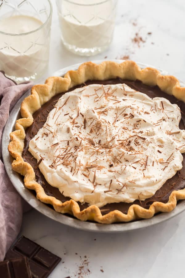 whole chocolate pie with whipped cream and two glasses of milk in the background