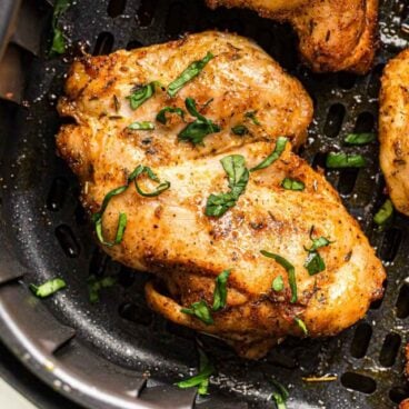 close up image of boneless chicken thigh in air fryer.