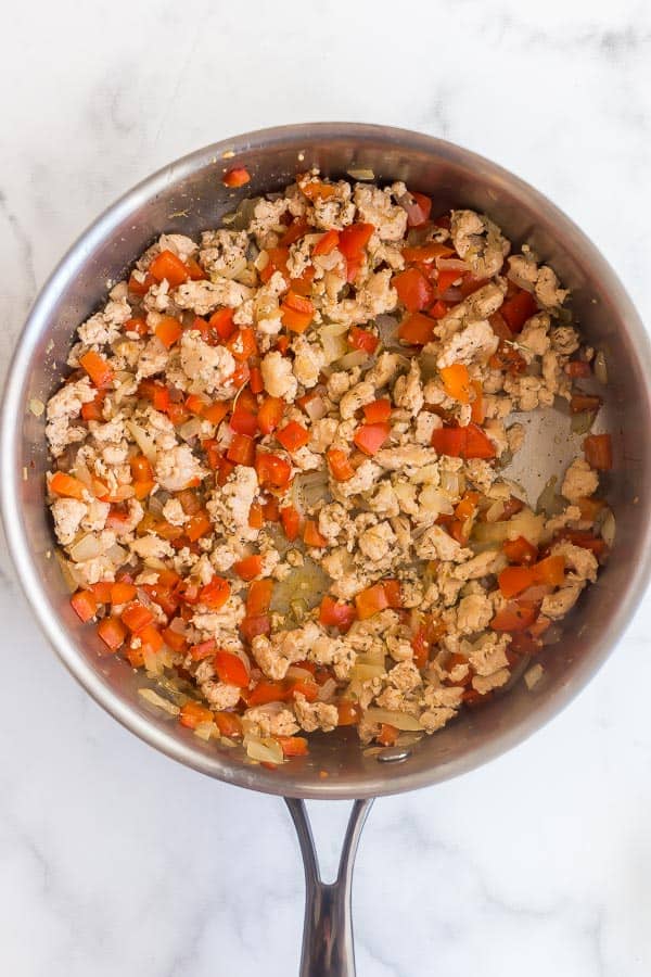 cooked onions and peppers with chicken sausage in pan