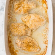 overhead image of white baking dish with four baked chicken breasts