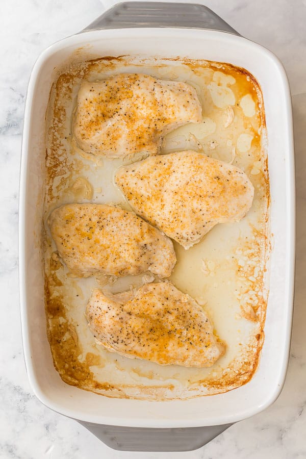 overhead image of white baking dish with four baked chicken breasts