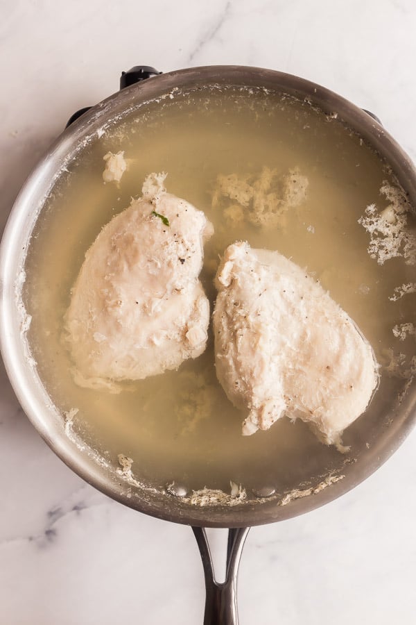 chicken breasts poaching in stainless steel pan