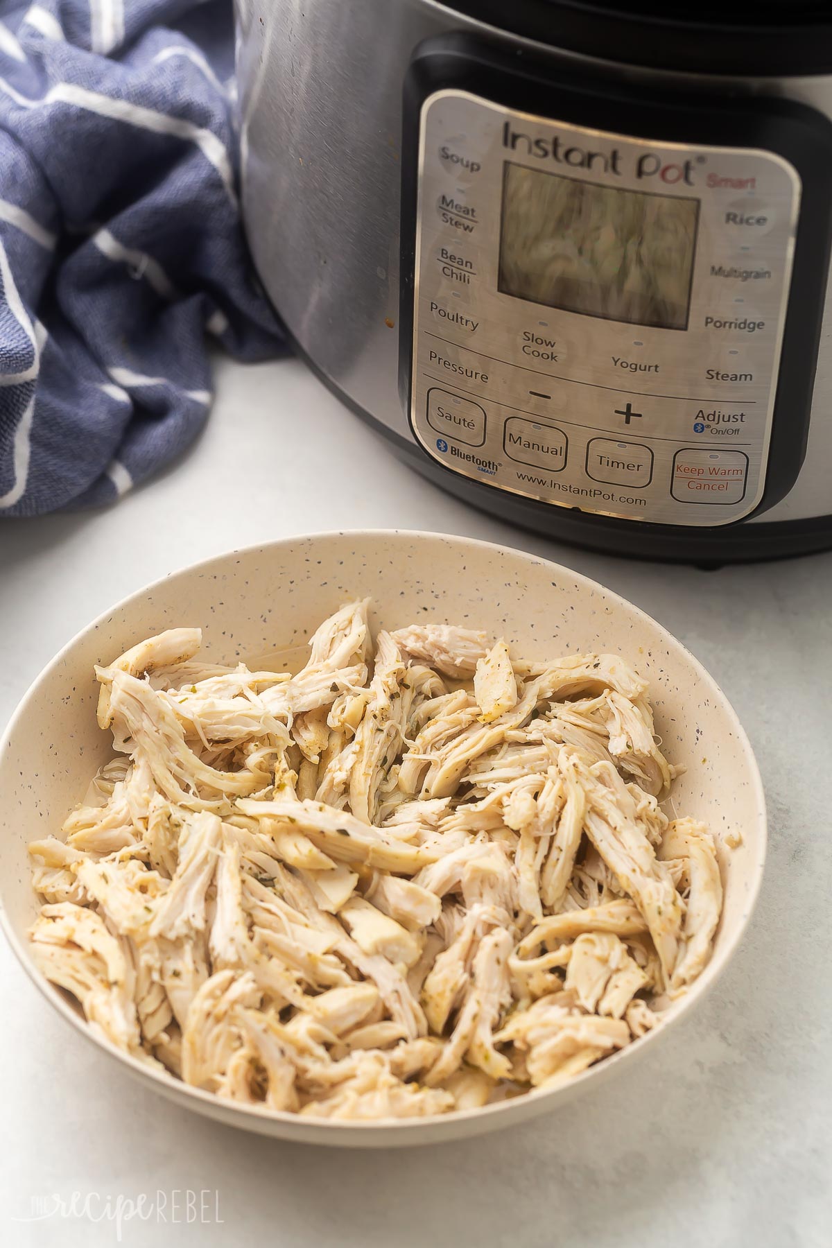 bowl of shredded chicken in front of instant pot.
