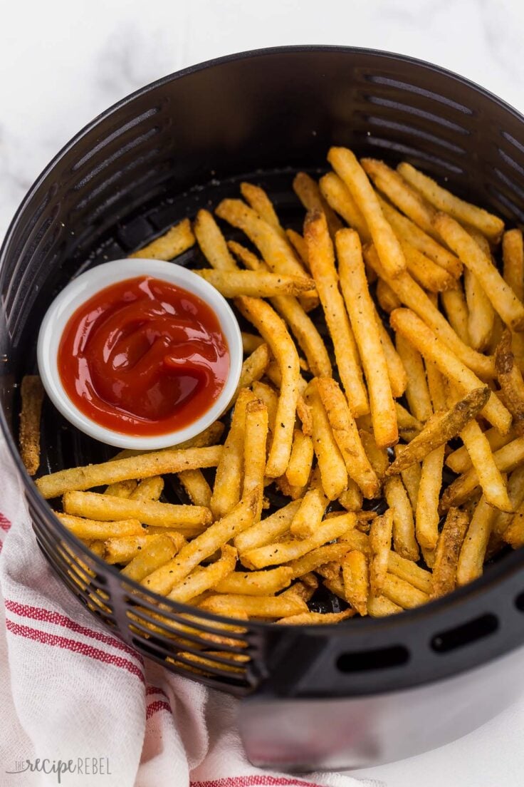 close up of crispy french fries in air fryer basket with ketchup