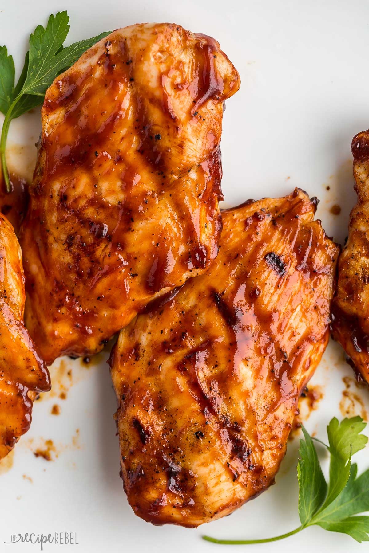 close up image of two grilled chicken breasts with bbq sauce