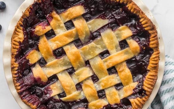 overhead image of baked blueberry pie with fresh blueberries