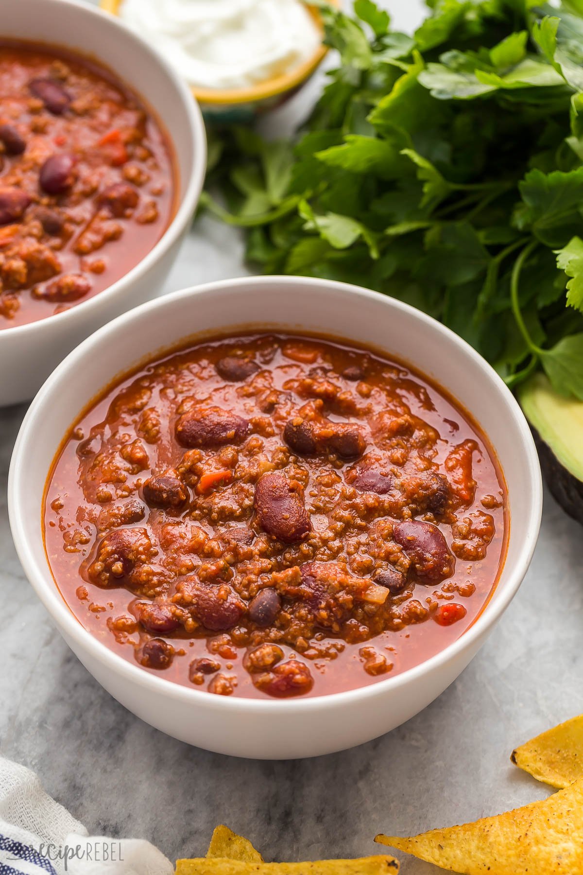 instant pot chili in a grey bowl with fresh parsley behind