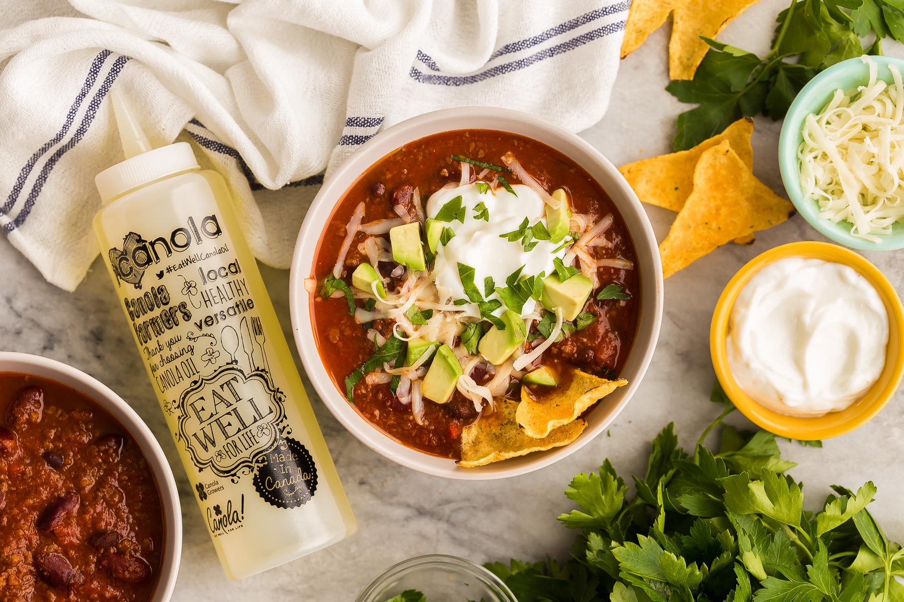 overhead image of instant pot chili with toppings and canola bottle