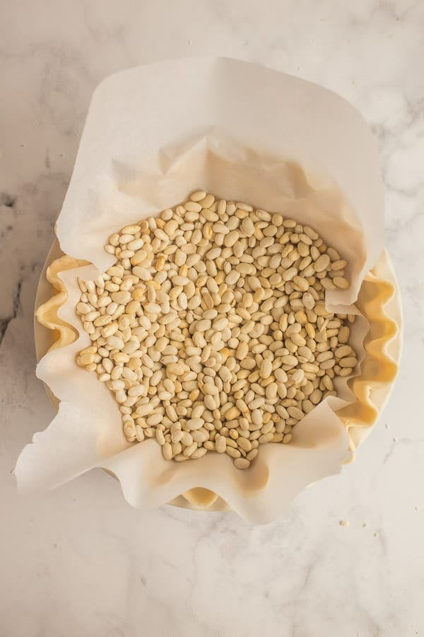 unbaked pie crust with parchment paper in the middle and pie weights