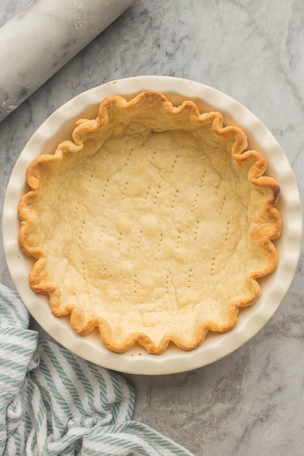 This easy Pie Crust recipe is perfect for any pie! Make it by hand or in the food processor, plus tips for storage and freezing. #pie recipes #dessert #baking | blind bake | blind baked pie crust | pastry | dessert overhead image of blind baked pie crust