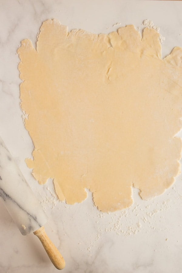 pie crust rolled out on marble with rolling pin