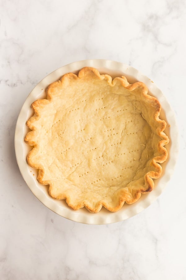 overhead image of blind baked pie crust on white background