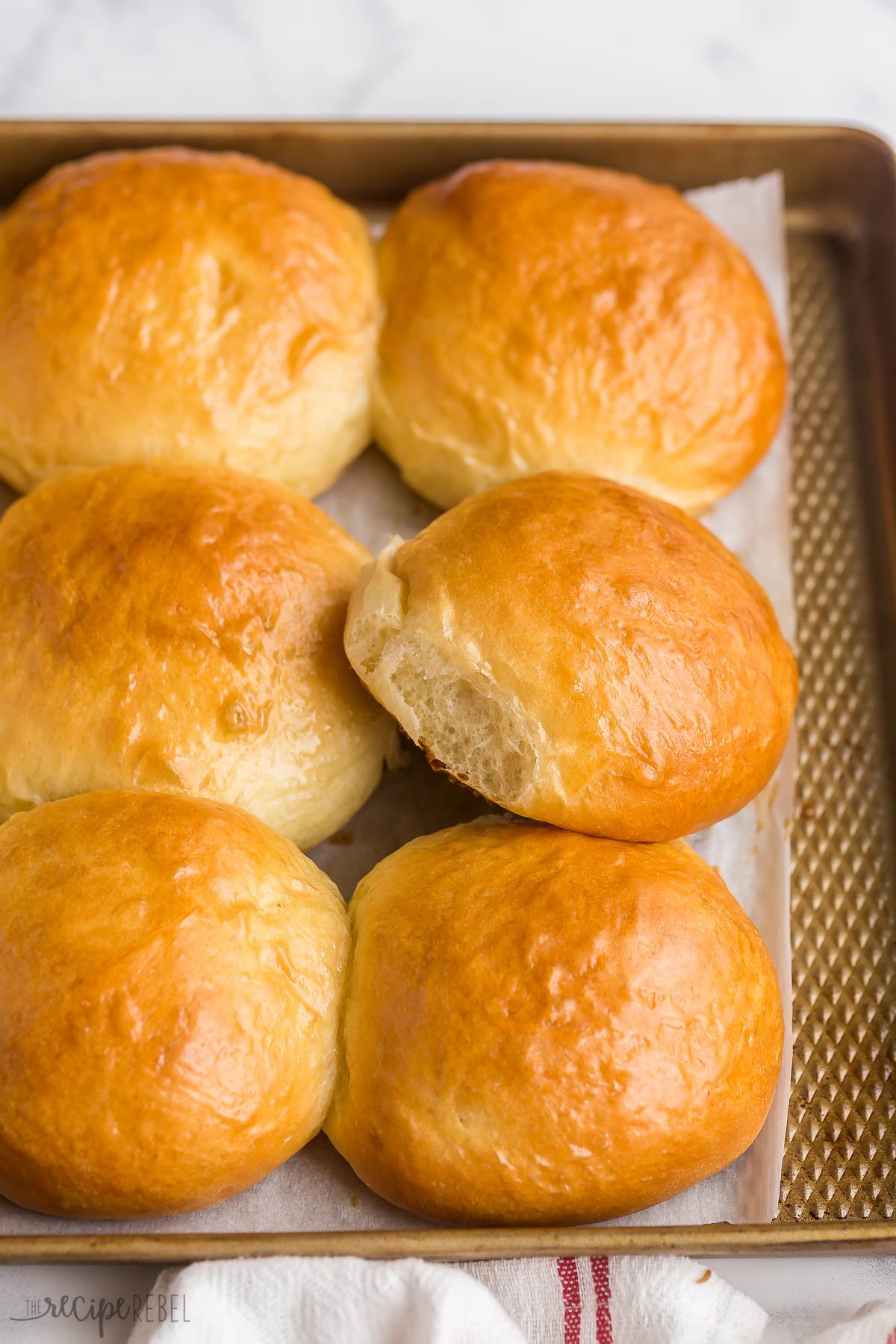 brioche burger buns on pan with one propped up