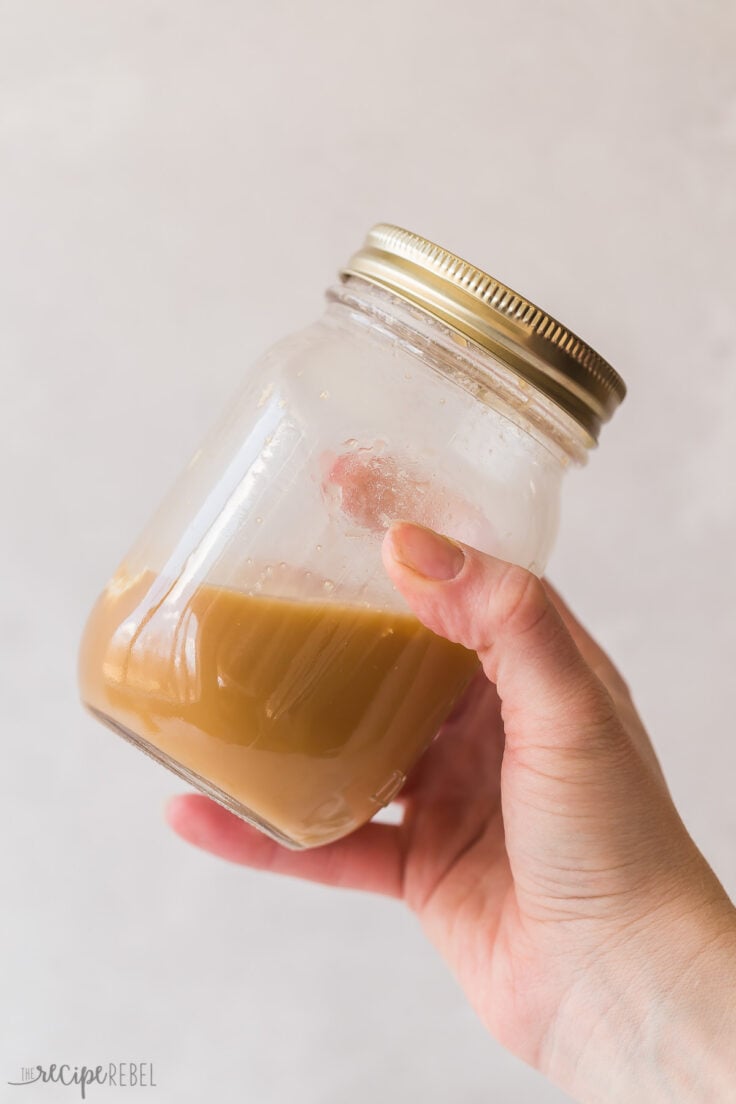 hand shaking coffee frappe in mason jar