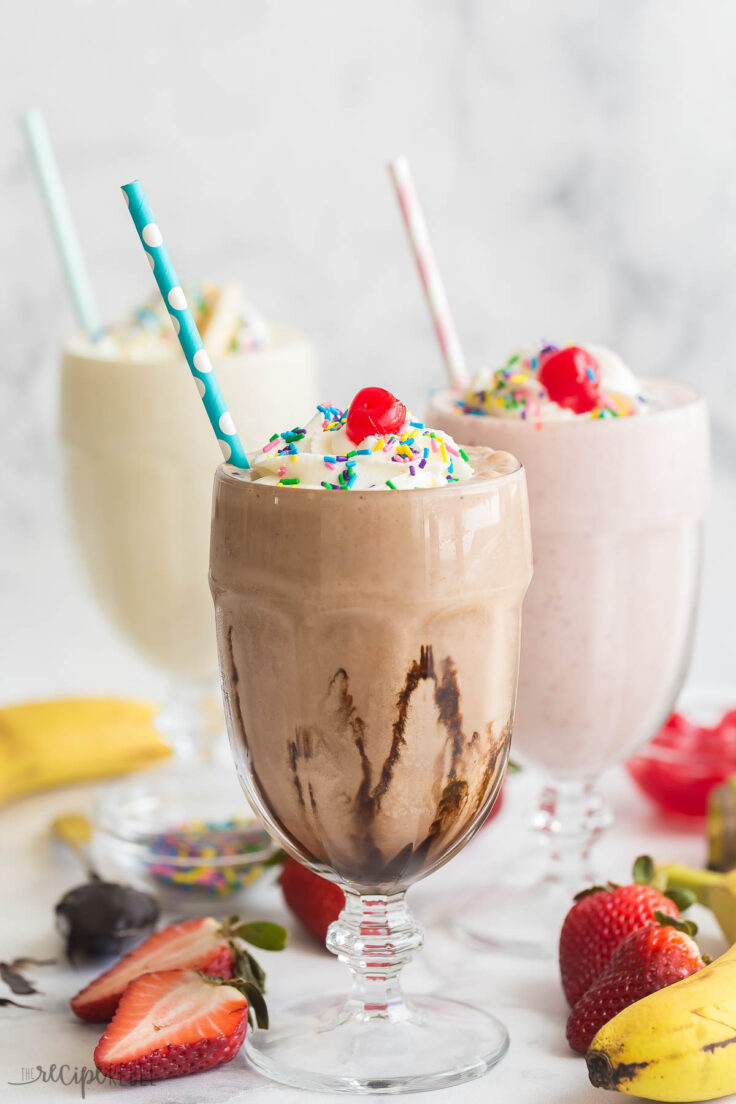 glass of chocolate milkshake in front of two other milkshakes