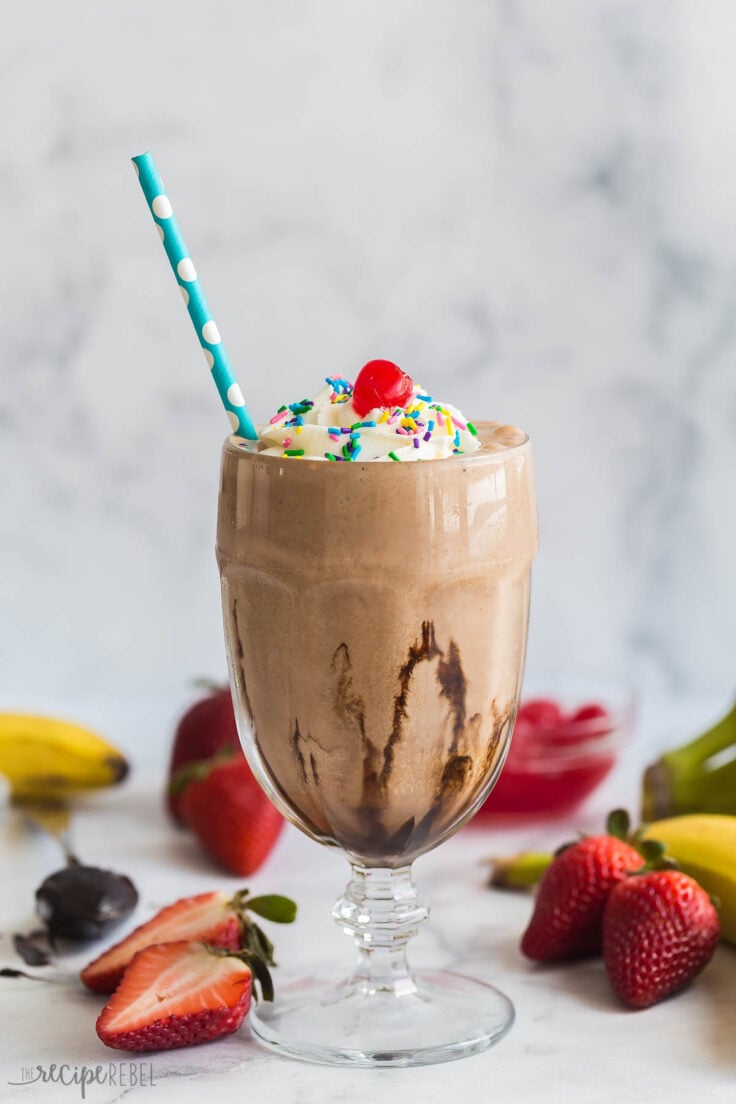 chocolate milkshake in tall glass with paper straw