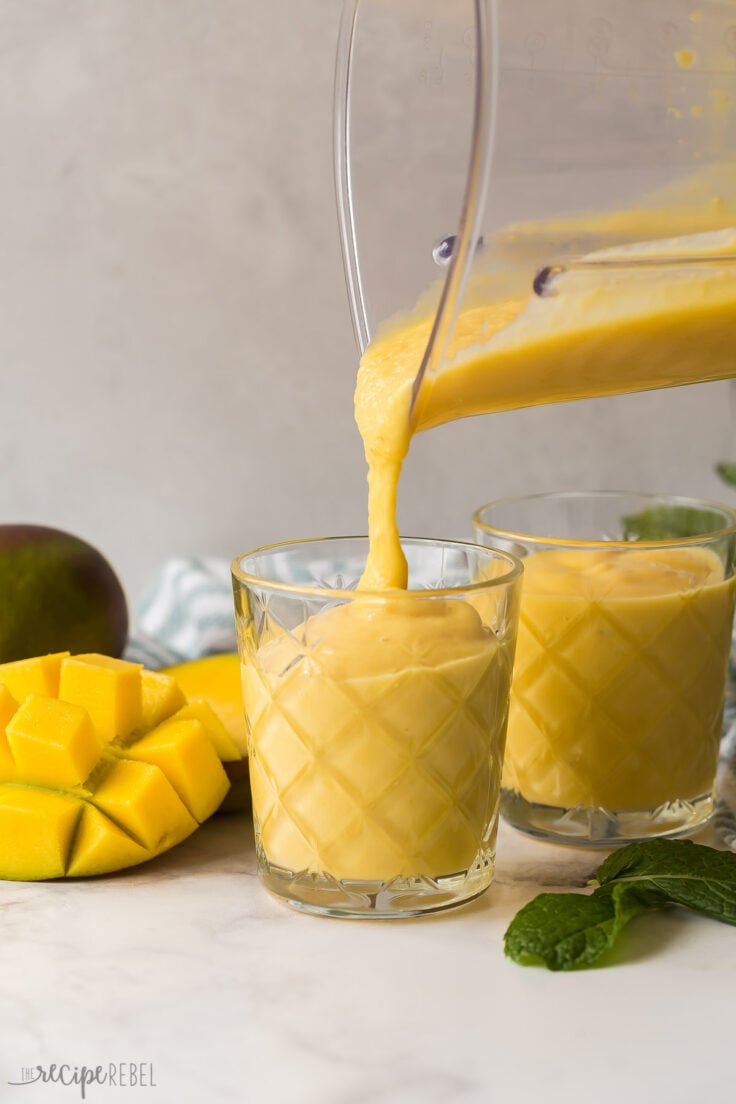 pouring mango smoothie into glass from blender