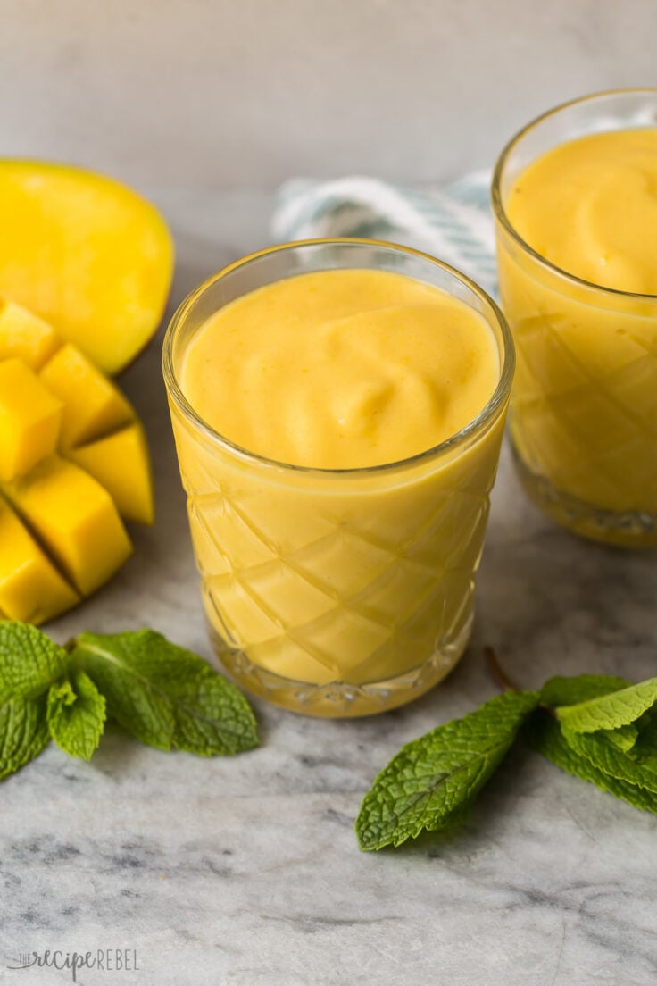 mango smoothie in glasses with fresh mango on the side