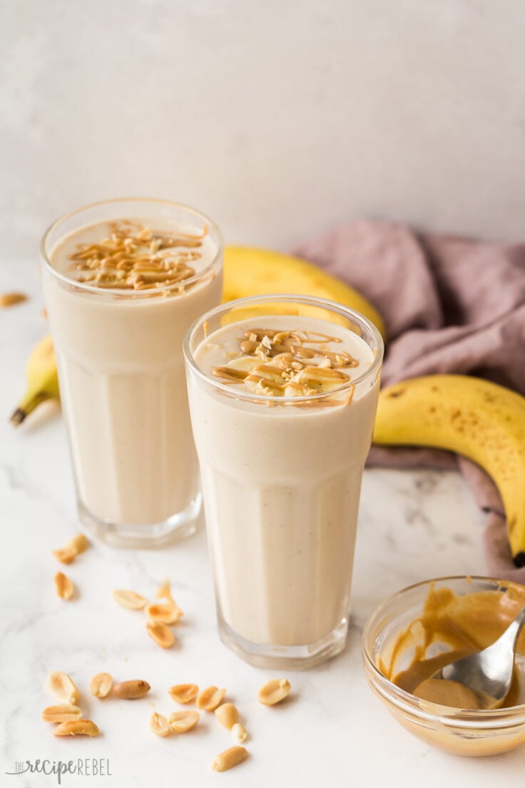 two glasses of peanut butter banana smoothie on white background