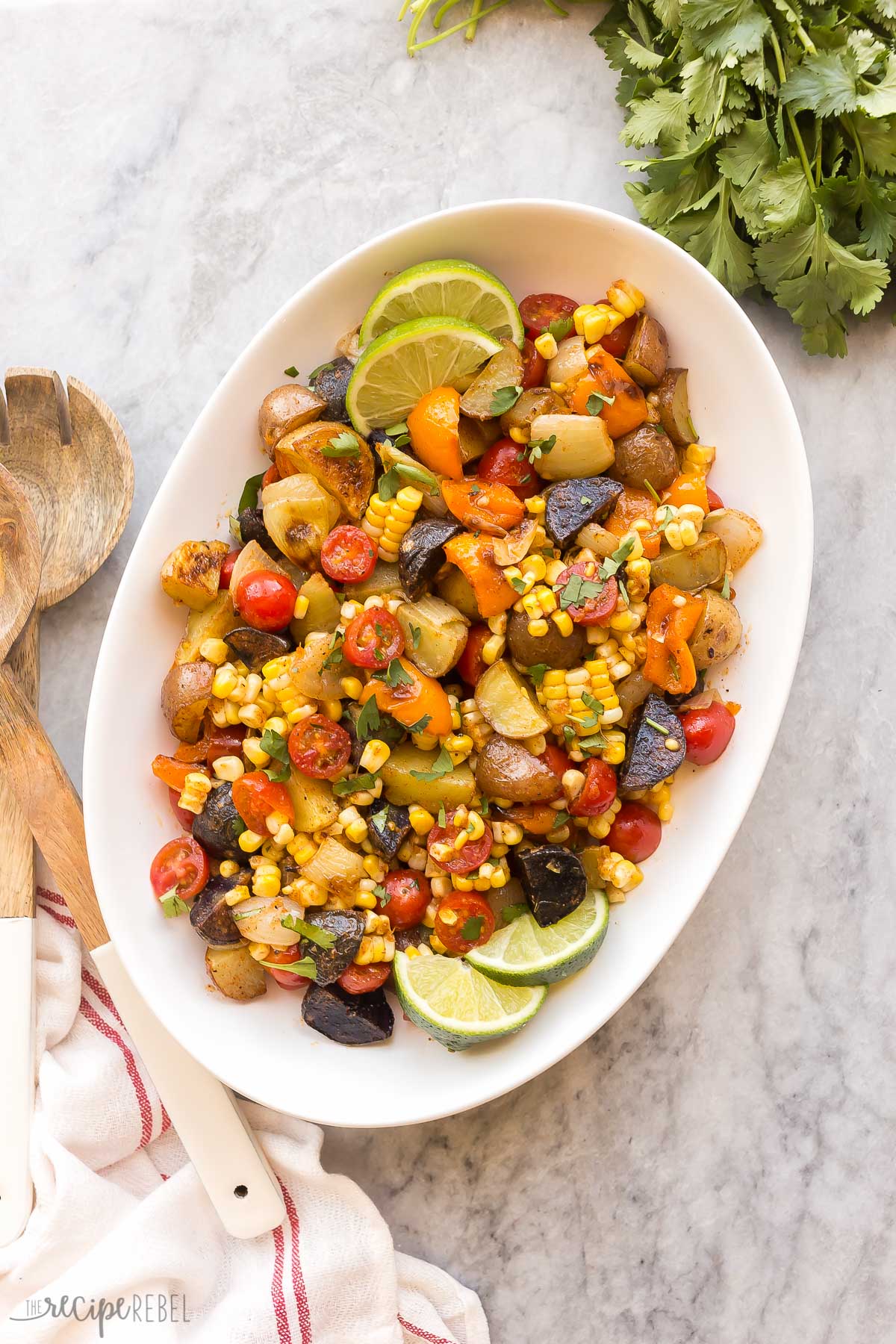This Southwest Potato Salad is made with grilled or roasted potatoes, peppers, corn on the cob and fresh tomatoes, tossed in a taco spiced vinaigrette! #potatoes #salad #recipes | cold salad | barbecue recipes | side dish overhead image of southwest potato salad in glass bowl