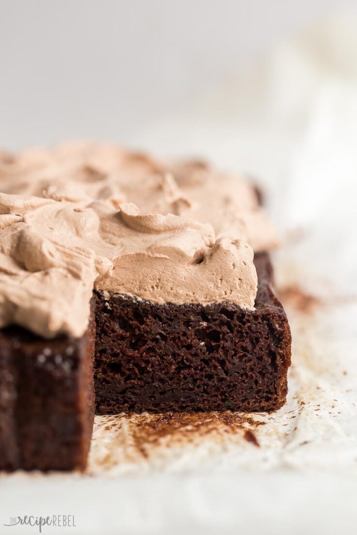 This is the BEST Chocolate Zucchini Cake! Perfectly moist, rich and fudgy and loaded with zucchini (but you'd never know)! Topped with chocolate whipped cream. #chocolate #dessert | zucchini cake | zucchini recipes | chocolate cake | best chocolate cake whole chocolate zucchini cake with one piece missing