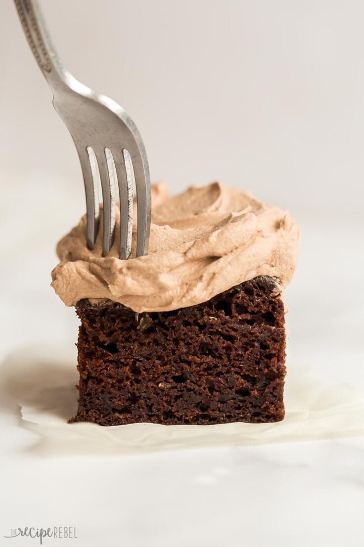 This is the BEST Chocolate Zucchini Cake! Perfectly moist, rich and fudgy and loaded with zucchini (but you'd never know)! Topped with chocolate whipped cream. #chocolate #dessert | zucchini cake | zucchini recipes | chocolate cake | best chocolate cake piece of chocolate zucchini cake with fork sticking in