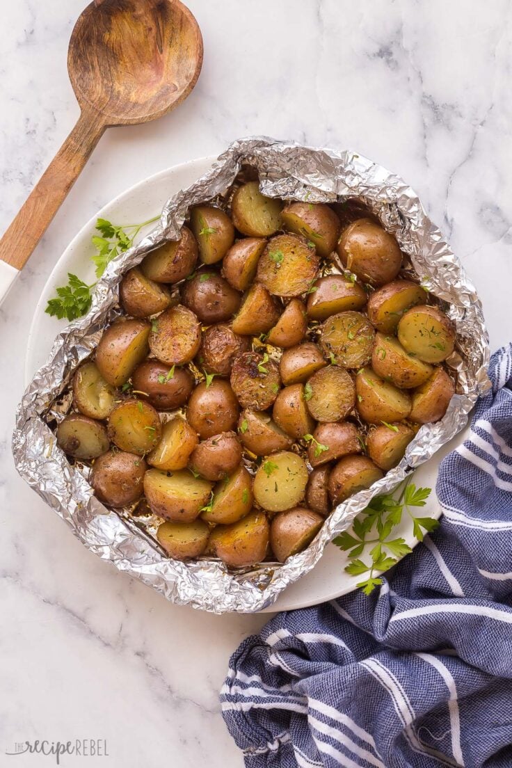 These easy Grilled Potatoes are cooked in a foil pack with butter, garlic and herbs for a simple summer side dish that's perfect for home or camping! #potatoes #grilling | grilling | grilled vegetables | camping recipes | camping meals overhead image of grilled potatoes in foil