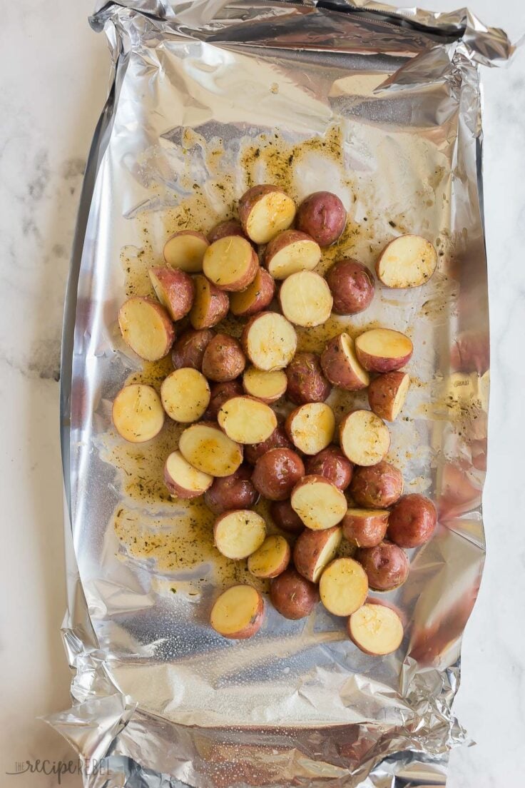 halved seasoned potatoes in foil ready to grill