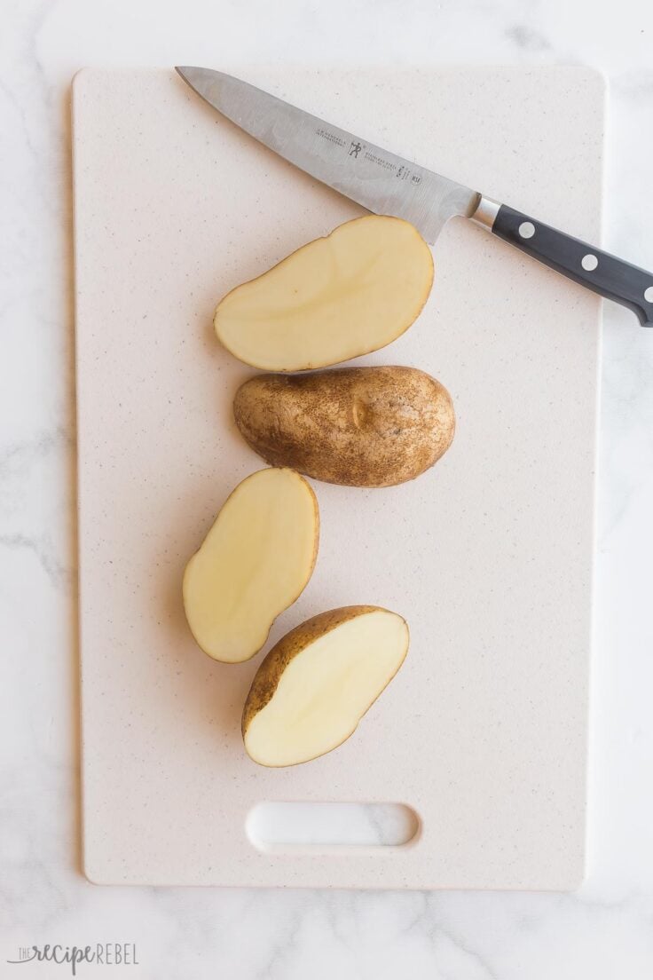 cutting russet potatoes in half on cutting board