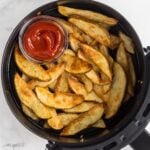 square image of air fryer potato wedges in air fryer basket