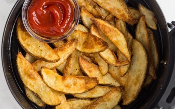 square image of air fryer potato wedges in air fryer basket