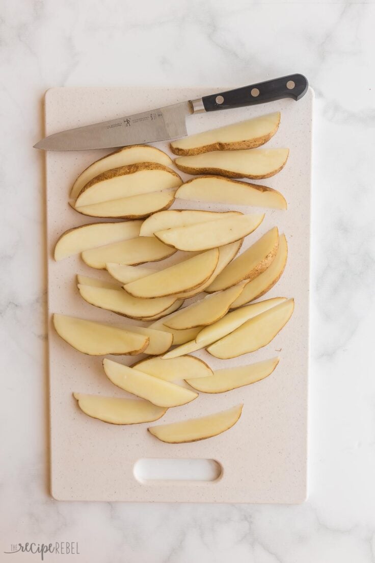 all potatoes cut into wedges on cutting board